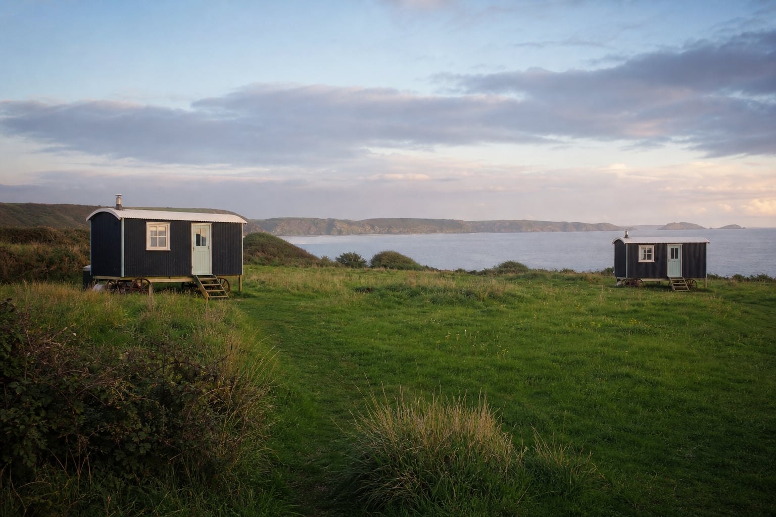 Wide view of two huts spaced across the meadow