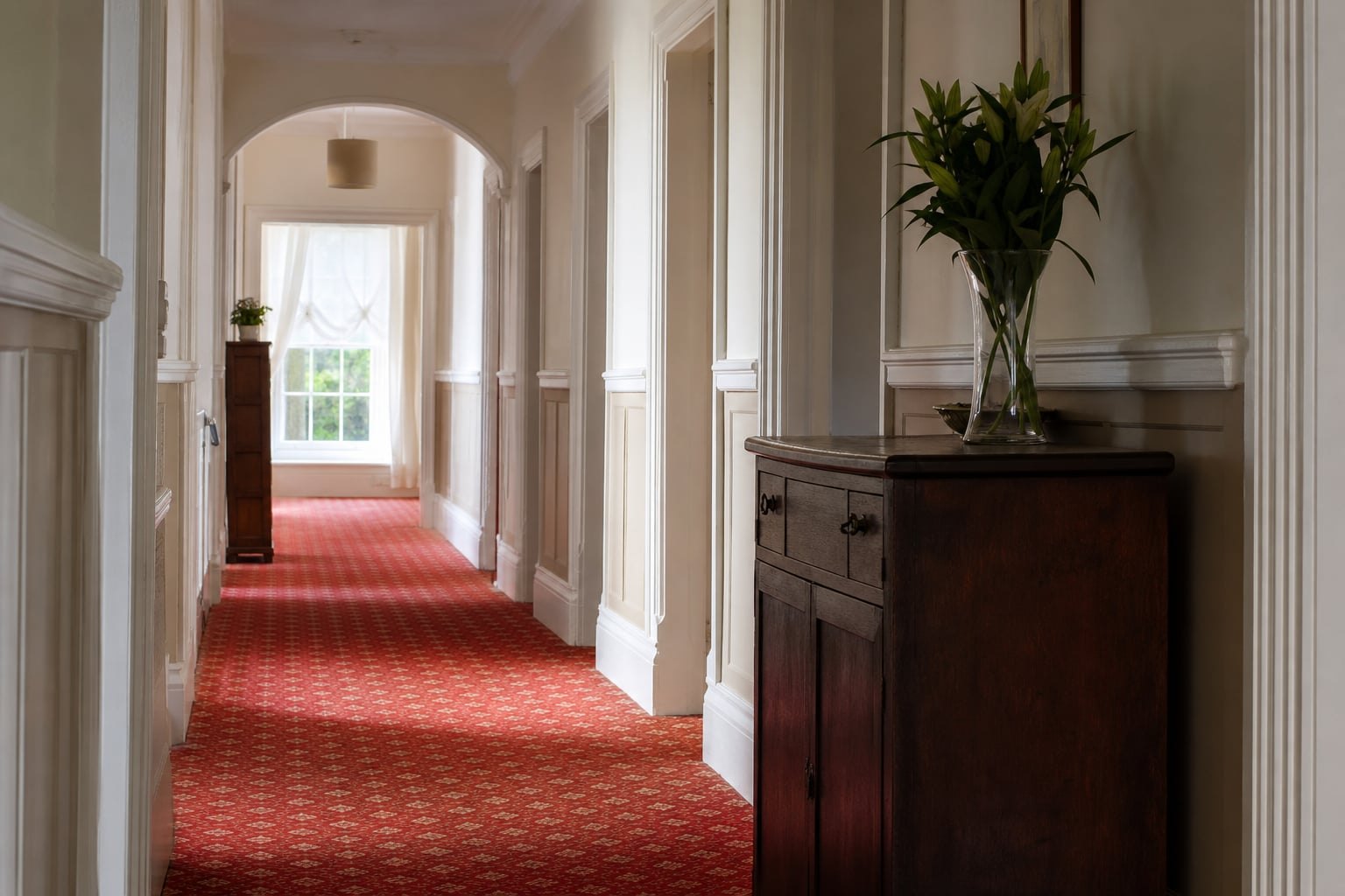 Carpeted guest-house corridor with soft daylight